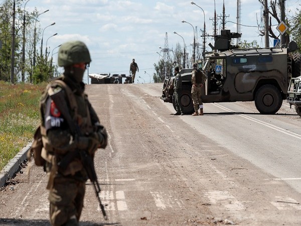 Service members of pro-Russian troops stand guard on a road before the expected evacuation of wounded Ukrainian soldiers from the besieged Azovstal steel mill in Mariupol. (PC: Reuters)