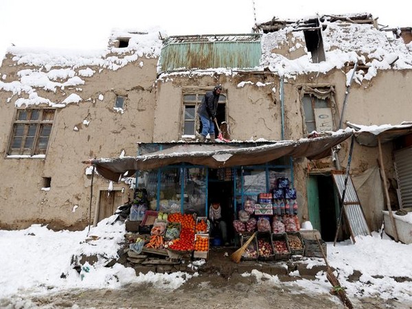 An Afghan man removes snow from his shop during a snowfall in Kabul, Afghanistan