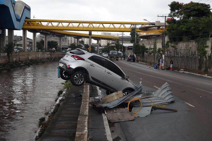 A car pushed by floods to a channel is seen after heavy rains in Vila Prudente neighbourhood in Sao Paulo.