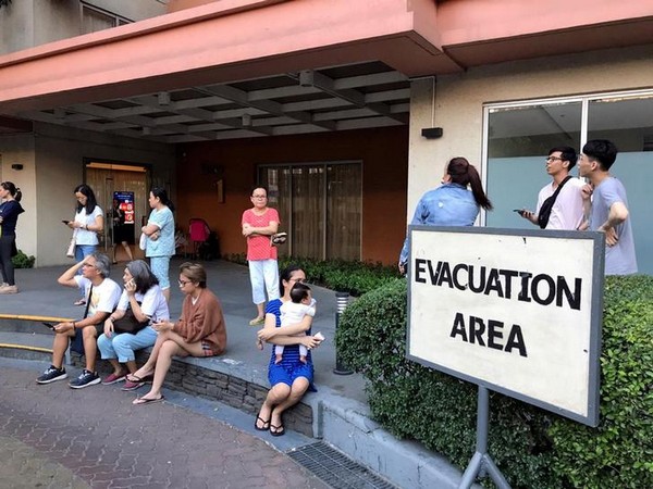 Residents sit outside after being evacuated from the condominium building after an earthquake in Makati City, Philippines (image source: Reuters)