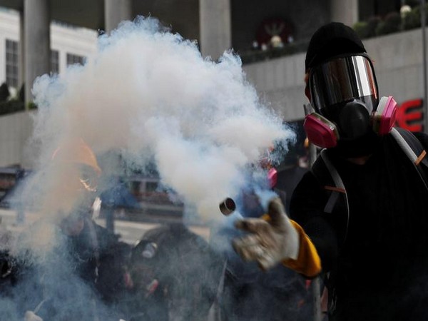 An anti-government protester throws back a tear gas canister during a clash with riot police in Hong Kong