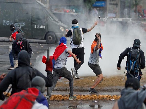 Demonstrators throw stones and tear gas canister during a protest in Santiago on Monday. Photo/Reuters