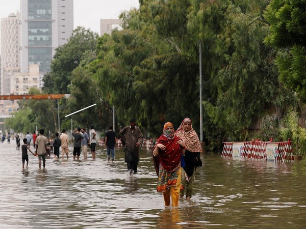 People wade through a flooded road after the monsoon rain, as the outbreak of the coronavirus disease (COVID-19) continues, in Karachi.