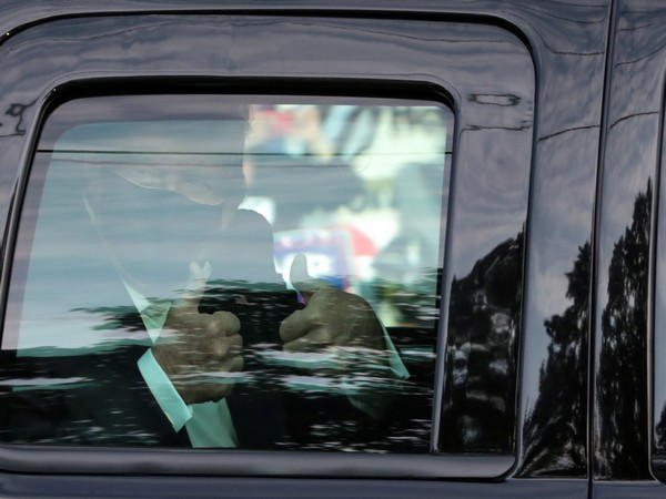 U.S. President Donald Trump gives a thumbs up to supporters as he rides by in the presidential motorcar in front of Walter Reed National Military Medical Center on October 5 (Credit: Reuters)