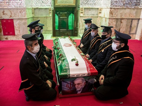 Mourners sit next to the coffin of Iranian nuclear scientist Mohsen Fakhrizadeh during the burial ceremony at the shrine of Imamzadeh Saleh, in Tehran, Iran. (Photo Credit: Reuters) 