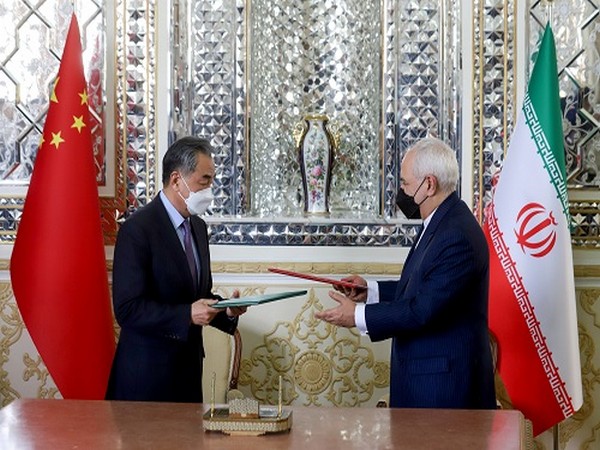 Iran's FM Mohammad Javad Zarif and China's FM Wang Yi exchange documents during the signing ceremony of a 25-year cooperation agreement, in Tehran, Iran March 27, 2021. (Photo Credit: Reuters)