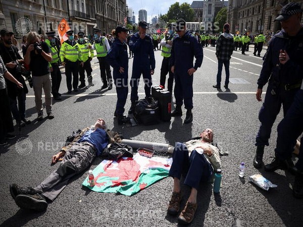Police officers approach protesters chained to each other during an Extinction Rebellion climate activists' protest [Image Credits: Reuters]