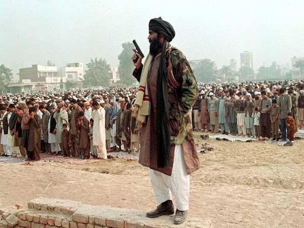 Pakistan: A supporter of terrorist Masood Azhar stands guard as people offer Eid-Al-Fitr prayers led by him