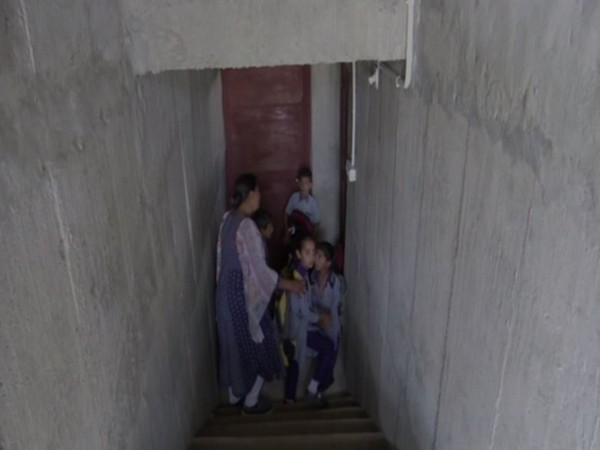 Students and teacher getting inside a bunker that has been constructed at a Government Primary school in Rajouri district 