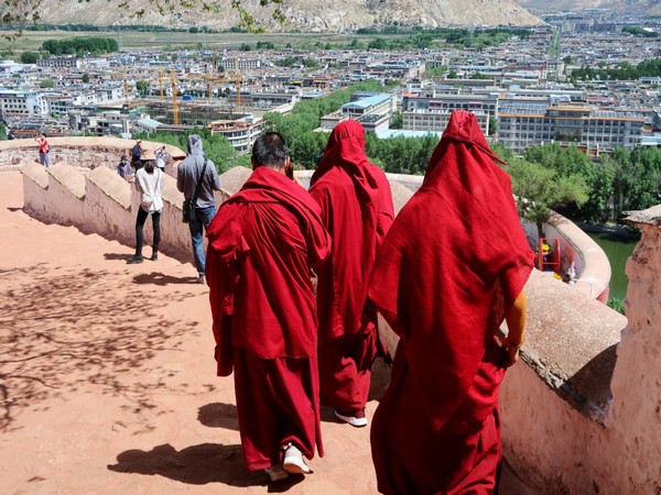 Tibetan Buddhist monls walk on the grounds of the Potala Palace overlooking the city of Lhasa, Tibet (Image CreditL Reuters)