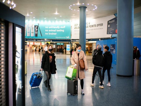 People wearing face masks walk along Penn Station in New York