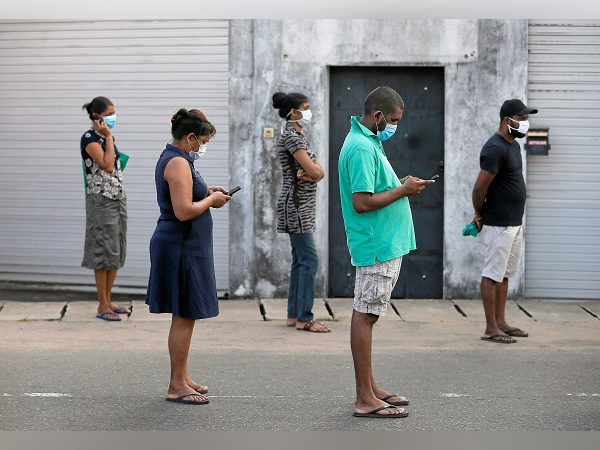 People maintain the one-meter distance in-between each other as they stand in a line to buy groceries at a supermarket. (Photo Credit: Sri Lanka)