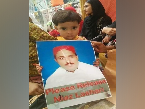 A boy holding a photo of late Niaz Lashari