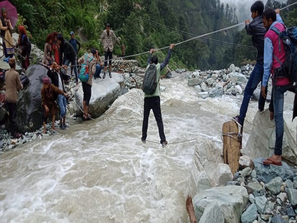 Villagers cross river with ropes as Forest Jeep is currently blocked in Sankri due to landslides. Photo/ANI