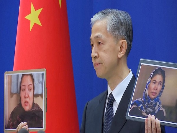 China's Foreign Ministry spokesman Wang Wenbin holding up images of witnesses who described sexual abuse in Xinjiang (Photo Credit - Reuters)