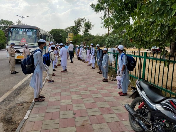 Students observing social distancing as they wait to board a bus to Bihar. [Photo/ANI]