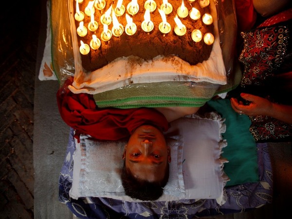 A man laying down with oil-fed lamps on his body in Nepal. (Photo Credits: Reuters)