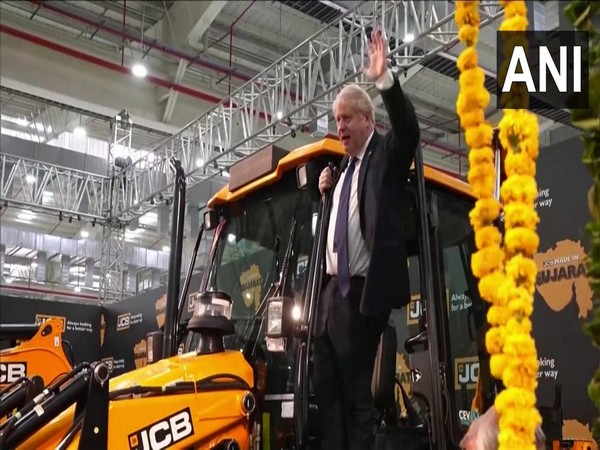 British Prime Minister Boris Johnson waving on a JCB  machine at its Gujarat factory