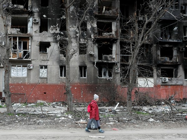An elderly woman walks past a residential building heavily damaged during Ukraine-Russia conflict in the southern port city of Mariupol (Photo Credit: Reuters)