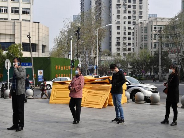 People wearing face masks line up outside a supermarket in Wuhan