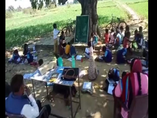 The students of the school on Wednesday were seen studying under a tree and were forced to sit on the ground. Photo/ANI