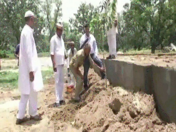 One of the person fulfilling his planting target as he is watched by authorities