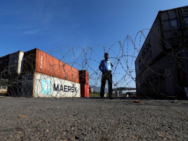 A police officer stands behind barbed wires near shipping containers used to block the road in Islamabad ahead of Azadi March on Tuesday.