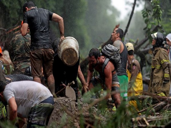 People and rescue workers are seen at the site of a mudslide after heavy rains, in Rio de Janeiro, Brazil (Photo Credit: Reuters)