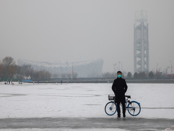 A man wearing a face mask stands on a frozen canal near the closed loop 