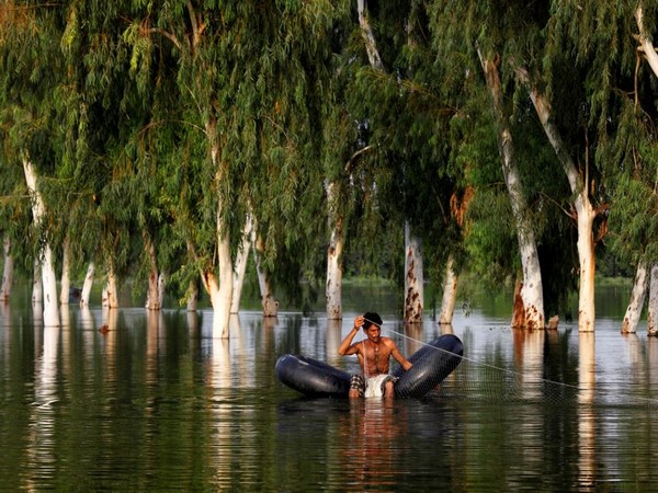 A man fishes on a flooded road in Pakistan's Muzaffargarh district of Punjab province (Photo Credit: Reuters)
