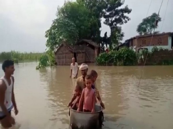 Residents here are forced to wade through knee-deep water in Bihar on Tuesday. Photo/ANI