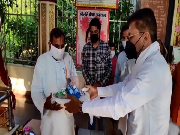 BJP MLA distributing COVID-19 kit (masks, sanitisers, PPE kits) to priests in Kanth village of Moradabad. (Photo/ANI)