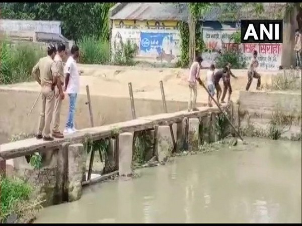 Two policemen in Bulandshahr watch children take out dead body from a canal.