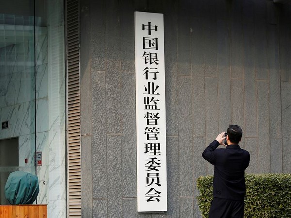 Man takes pictures of a sign of China Banking Regulatory Commission (CBRC) at its office in Beijing (Photo Credit: Reuters)