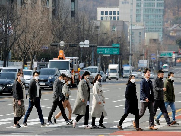 People wearing masks to protect them from coronavirus walk on a pedestrian crossing in downtown Seoul