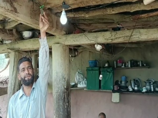 A villager lights up a bulb in his house in Kadola village (Photo/ANI)