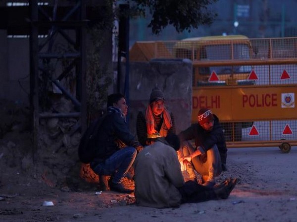 Men sit next to a bonfire on a road side in New Delhi on Saturday. Photo/Reuters