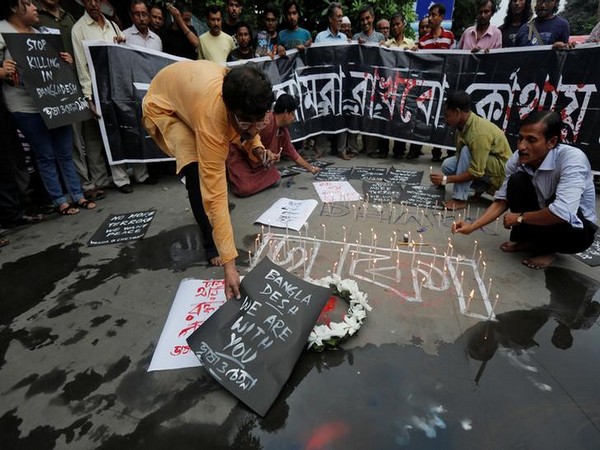 A man places a sign as others light candles during a vigil in Kolkata, India, to show solidarity with the victims of the attack at Holey Artisan restaurant in Dhaka