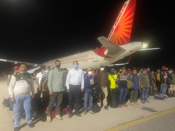 Indian nationals stand behind an Air India plane at Tajikistan's Dushanbe airport.