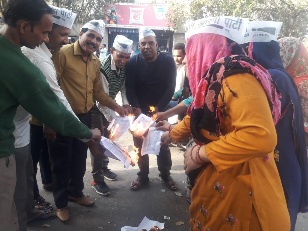 AAP workers burning the copies of BJP's 2014 LS poll manifesto on Sunday. Photo/ANI