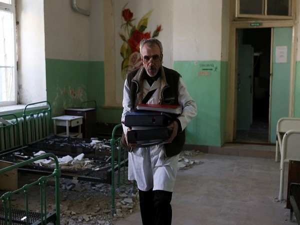 A man carries file folders at a damaged psychiatric hospital after it was hit in a military strike (Photo Credit: Reuters)