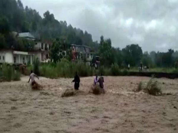 Local resuing three people stranded in the flash flood in a local rivulet in Hamirpur in Himachal Pradesh on Monday. Photo/ANI