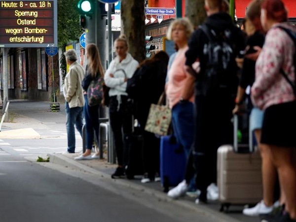 People waiting for a metro train next to a sign which reads 