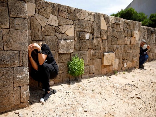 An Israeli man take cover as a siren sounds warning of incoming rockets from Gaza, during cross-border hostilities, in the southern Israeli city of Ashkelon