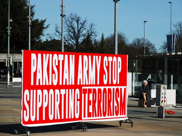 A banner reading 'Pakistan Army Stop Supporting Terrorism' displayed outside UNHRC headquarters in Geneva.