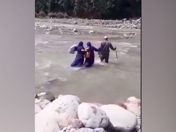 Healthcare workers in Jammu and Kashmir's Rajouri crossing a river to conduct COVID-19 vaccination drive. (Photo/ ANI)
