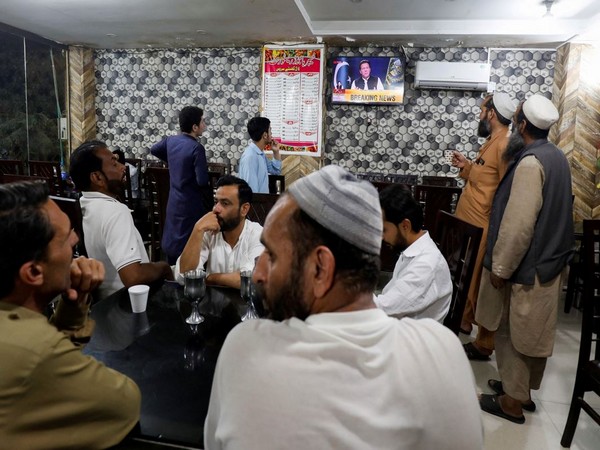 People watch the speech of Pakistani Prime Minister Imran Khan on a television screen, at a cafe in Islamabad, Pakistan (Photo Credit: Reuters)