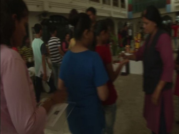 A teacher makes children use hand sanitizer at a board exam center in Ahmedabad [Photo/ANI]