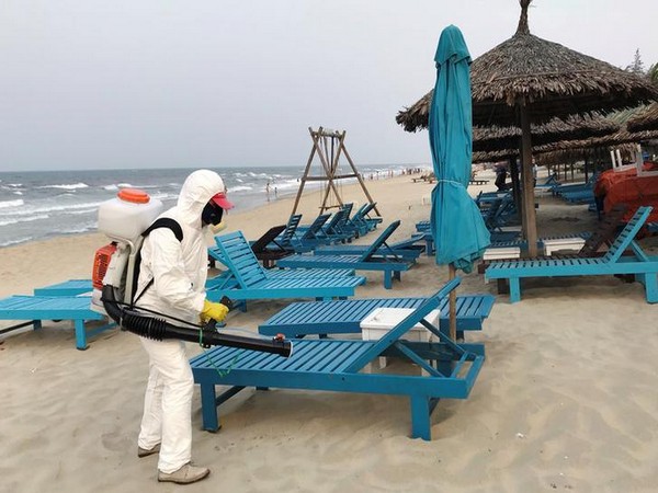 A health worker sprays disinfectants to protect against the coronavirus on a beach in Hoi An