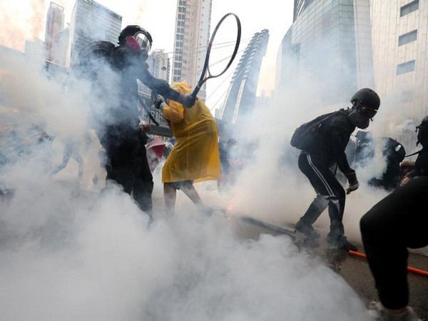 Demonstrators react to tear gas as they clash with riot police during a protest in Hong Kong